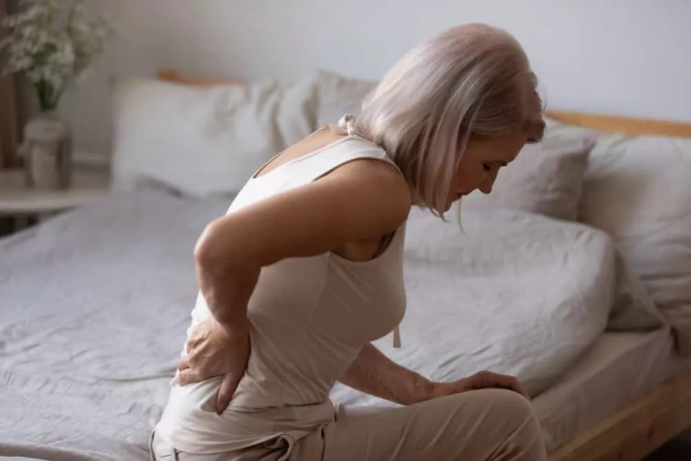 Une femme assit sur le bord d'un lit ayant de l'ostéoporose