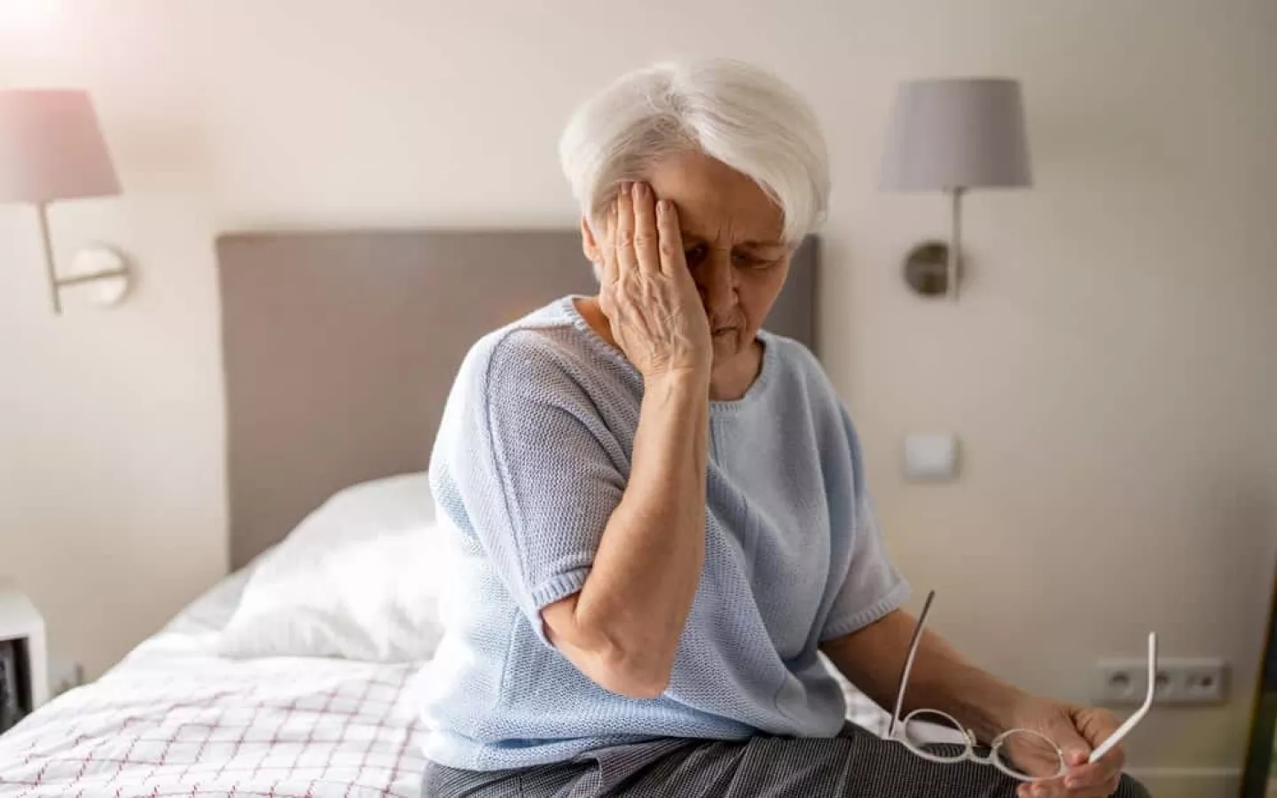 Une personne âgée qui assit sur un lit à la suite d'un vertige