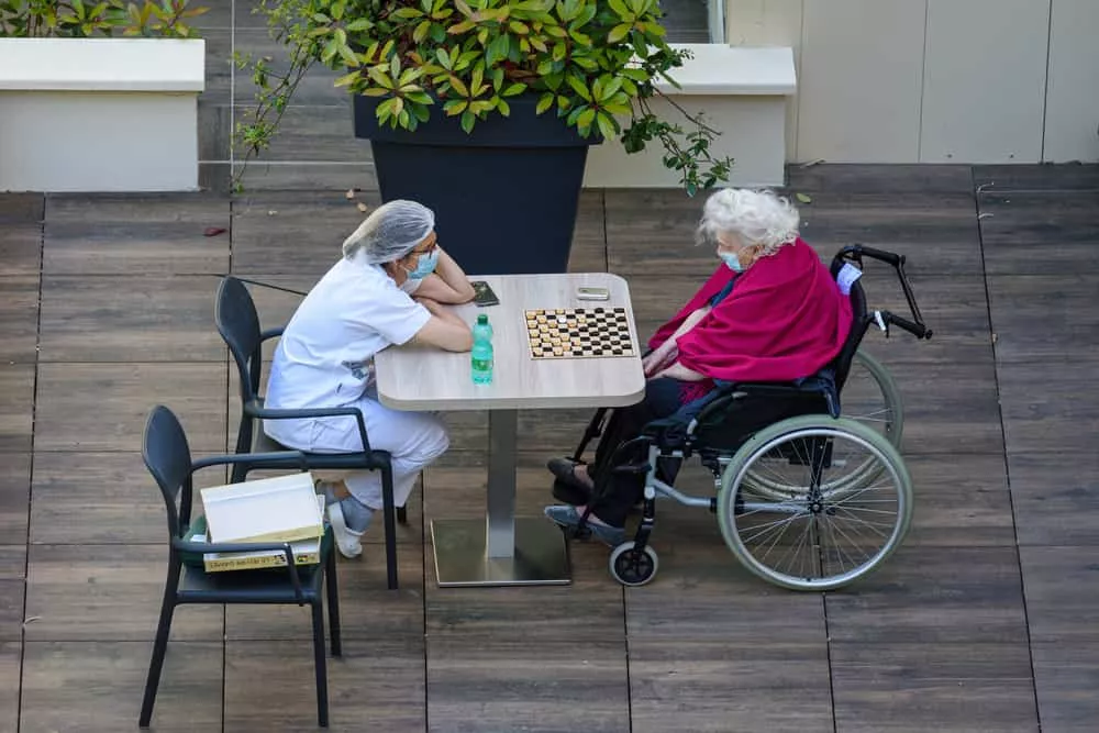 infirmière qui joue au jeu de dames avec une personne âgée dans un ehpad