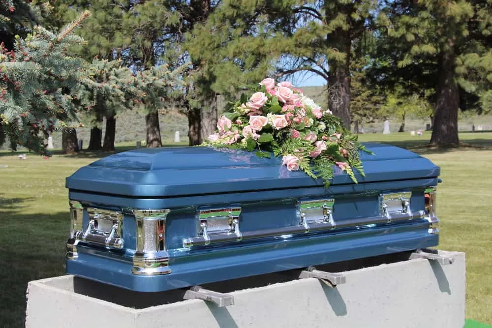 Cercueil de couleur bleue ornée de fleurs roses