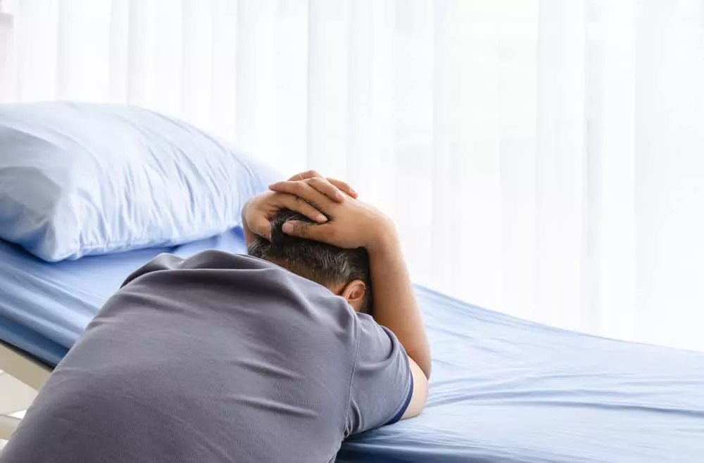 Un homme pleure sur le lit d'hôpital en faisant le deuil de sa conjointe décédée