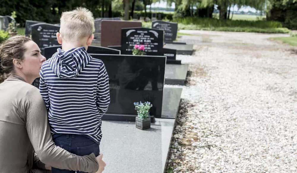 Un enfant fait le deuil de sa grand-mère devant sa tombe